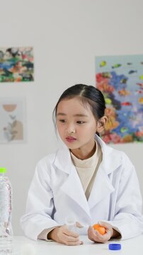 Young Asian Girl in Lab Coat Performing Bernoulli's Principle Science Experiment