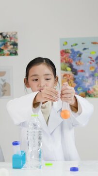 Asian Girl Demonstrating Bernoulli's Principle with Ping Pong Ball and Tube