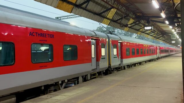 indian railway ac three tier coach parked at platform under covered station roof