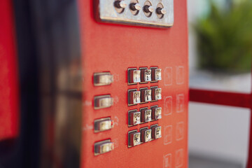 Obraz premium A close-up of vintage black telephone handset, with a hand pressing buttons on classic red public telephone. Concepts of retro communications and network technology.