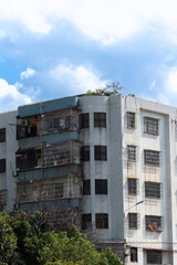 Fototapeta premium Dilapidated multi-story apartment building with rusted balconies under cloudy sky
