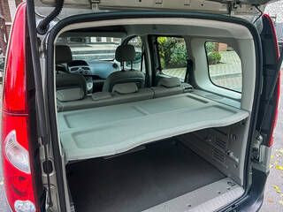 Minivan with folded seats and open trunk area seen in urban setting during daylight