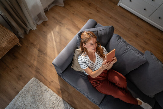 Woman relaxing at home reading digital ebook