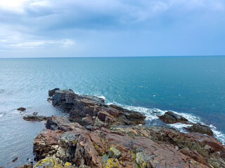 View of rocky coastline and ocean under cloudy sky on a chilly afternoon by the sea