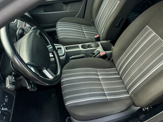 Interior view of a car showing two front seats with fabric design and steering wheel in a well-lit setting