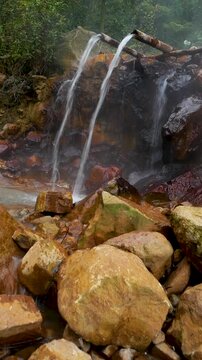 Vertical view Seamless Loop geothermal stream flowing through volcanic rocks with steam vents in Curug Cikawah volcanic area, Bogor, West Java, Indonesia.