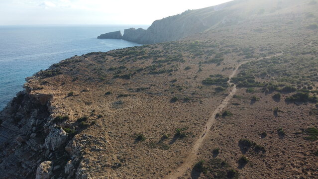 Stunning Seaside Cliff Pathway Scene. Serene Oceanfront Landscape With Rugged Trail And Bright Sunlight