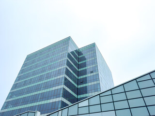 Fototapeta premium Modern office buildings stand under a cloudy sky in an urban area showcasing glass and steel architecture with geometric designs