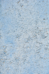 Fototapeta premium A close up shot of a white stucco wall with a rough grainy texture and subtle grey shadows on a weathered exterior surface