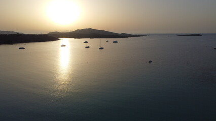 Naklejka premium Morning Glow Highlights Peaceful Seaside Scene. Soft Sunlight Reflects On Gentle Waves Near Distant Islands