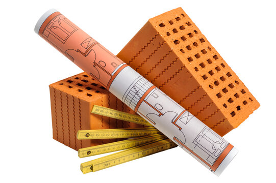 Symbolbild f&uuml;r Hausbau und Wohnungsbau mit Ziegel und Werkzeug isoliert als Freisteller &uuml;ber transparentem Hintergrund