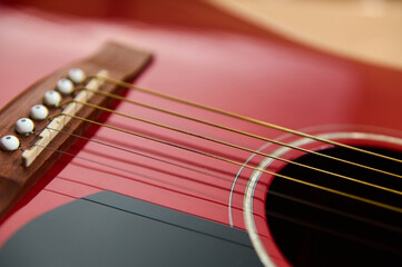 Fototapeta premium Red Acoustic Guitar Focused On Strings For Maintenance And Repair Practice