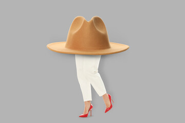 Female legs with large hat on gray background