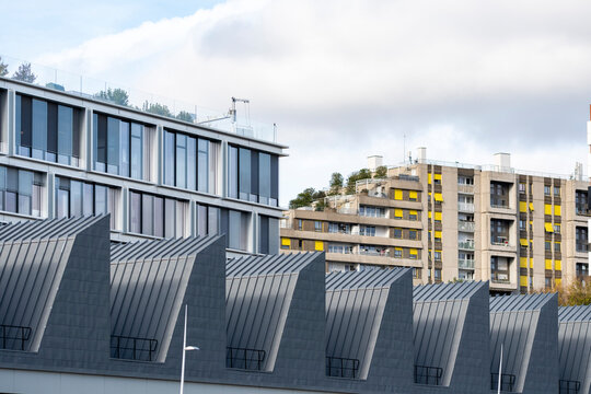 Modern architecture in Paris France combining an industrial roofline with urban apartment blocks under cloudy light showing facade rhythm and skyline scale