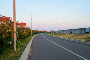 Modern asphalt bicycle path along sea embankment at sunset