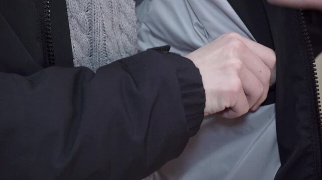 Inspection of the inner pocket of a winter jacket, Close-up of a person showing an inner zipper pocket in a black jacket
