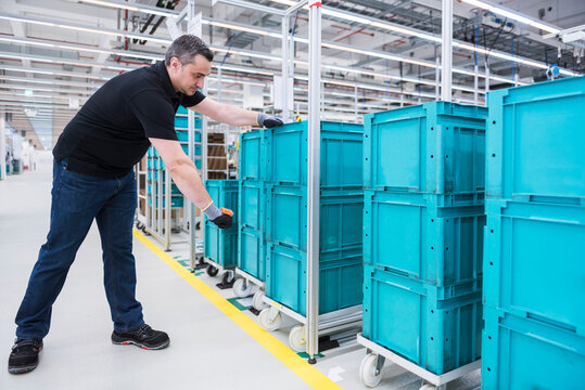Man scanning boxes on tugger train in industrial hall