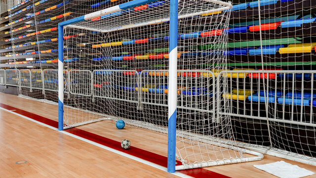 Indoor soccer goal with two balls on wooden floor