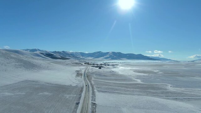 Aerial view snow-covered mountains and a winding road in winter landscape. A snow cowered road in Aragatsotn Province, Armenia, Caucasus. Snow-covered landscape stretches across the scene with mountai
