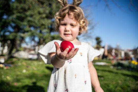 Little girl celebrating Easter with a red egg