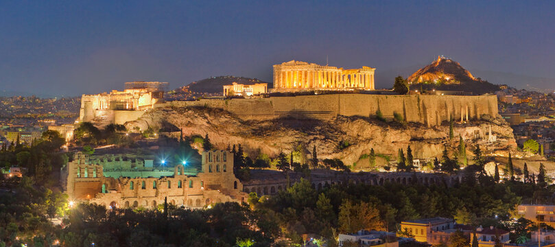 Aerial view of illuminated ancient ruins and monuments stand majestically against the twilight sky, a testament to history's enduring legacy, Athens, Central Athens Regional Unit, Greece.