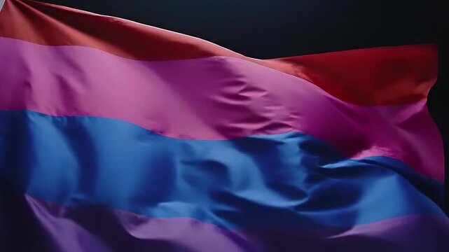 Bisexual Pride Flag Waving in the Wind Against a Dark Background.