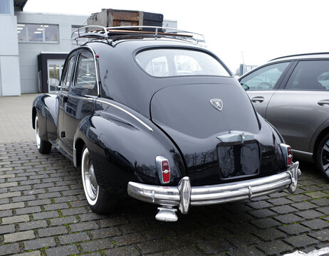 Itterbeck, Germany - January 13 2026 The rear of an old black Peugeot 203 C with suitcases on the roof.  The car is from 1955