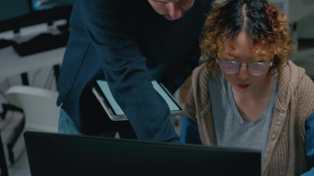Focused diverse software engineers and AI developers working on code on computer screens in a dark office. Concept of machine learning, digital transformation, and future technology innovation.