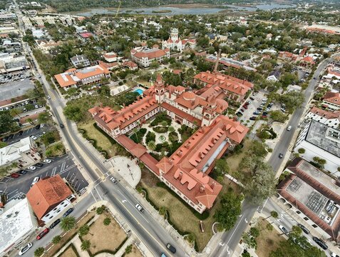 Aerial view of the grand, terracotta-roofed Lightner Museum standing proudly amidst the vibrant cityscape, its courtyard a verdant oasis, St. Augustine, Florida, United States.