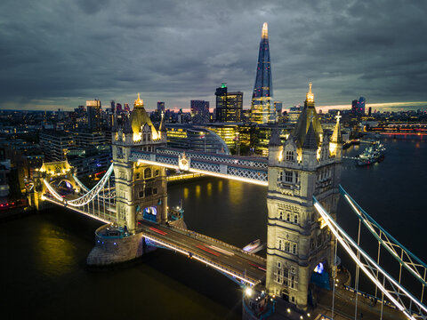 Aerial view of the iconic Tower Bridge glowing against the twilight skyline, with The Shard piercing the sky, London, Greater London, United Kingdom.