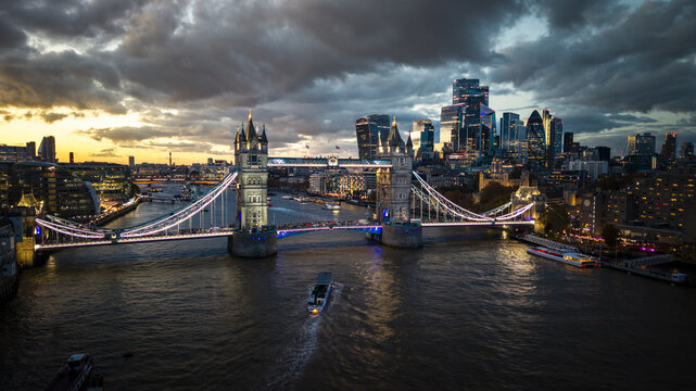 Aerial view of the iconic Tower Bridge illuminated against the twilight sky, with the modern skyline shimmering in the background, London, Greater London, United Kingdom.