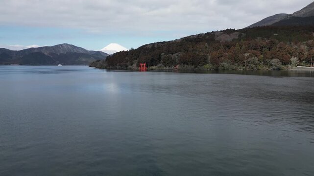 Peaceful view of Lake Ashi with calm water surface and mountain forest in background. Tranquil natural landscape in Hakone region. Overcast sky creating moody atmosphere at Japanese volcanic lake.