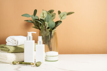 Skin care products in the bathroom. Face cream, serum bottle, jade roller and stack of towels. © nadianb