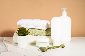 Skin care products in the bathroom. Face cream, serum bottle, jade roller and stack of towels. © nadianb