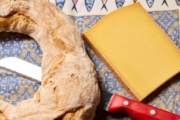 Tomme cheese. Wedge of French Tomme cheese and a ring-shaped bread roll. This type of cheese is very popular in France.