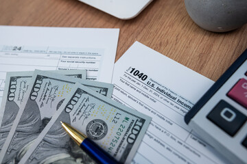 Financial tax documentation with calculator fountain pen and American dollar bills on office table