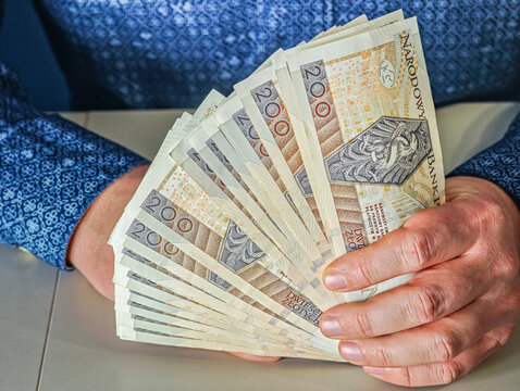 Close up of businessman hands holding stack of Polish Zloty paper money for commercial transaction