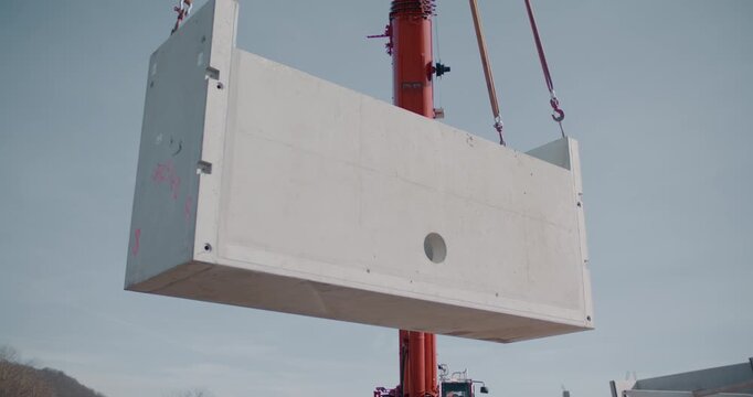 Crane lifting large precast concrete element at construction site