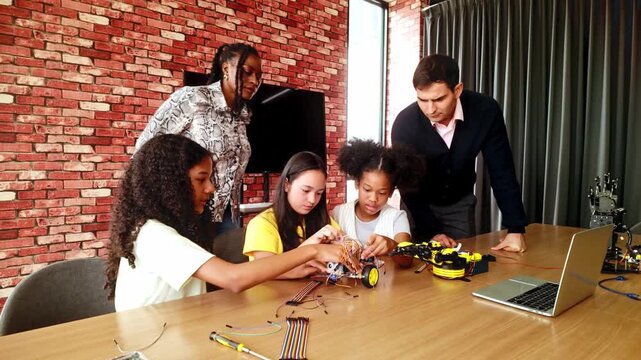 Students collaborate on a robotics project while two mentors guide them, with tools, wires, and a laptop in a modern classroom.