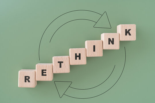 RETHINK text on wooden cube block with circle on green background