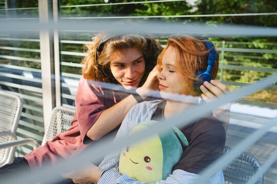 Urban youth sharing headphones in quiet togetherness with plush toy
