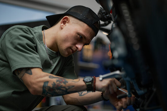 Mechanic fixing motorcycle in workshop with tool