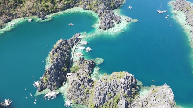 Aerial view of several boats floating on the teal waters near the jagged cliffs with some greenery, Coron, Mimaropa, Philippines.