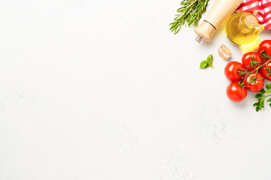 Spices, herbs and vegetables with olive oil on white kitchen table.