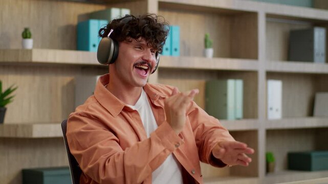 Active happy Caucasian business man listening music in headphones dancing at table businessman listen song smiling dance in office funny male guy company owner moving to audio rhythm enjoy work pause