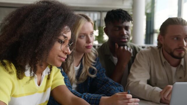 Group of five multiracial diversity university college students upset talking studying with laptop discuss difficult homework looking at computer talk solving decision learn study e-learning service