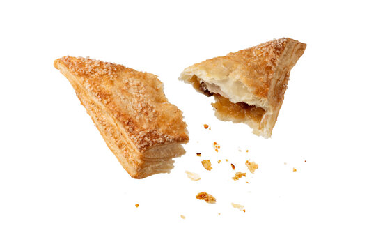 Broken in half fresh baked pastry puff pie apple turnover with crumbs flying falling isolated on white. Pastry card.