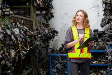 Worker holding a clipboard and checking electronic scrap in the factory