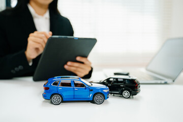 Car accident model with business professional reviewing claim on tablet. Auto insurance, damage...