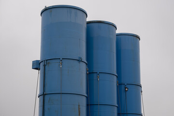 Blue industrial storage silos against cloudy sky close up